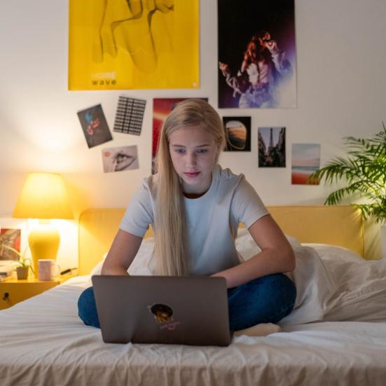 Teenagepige i seng med computer